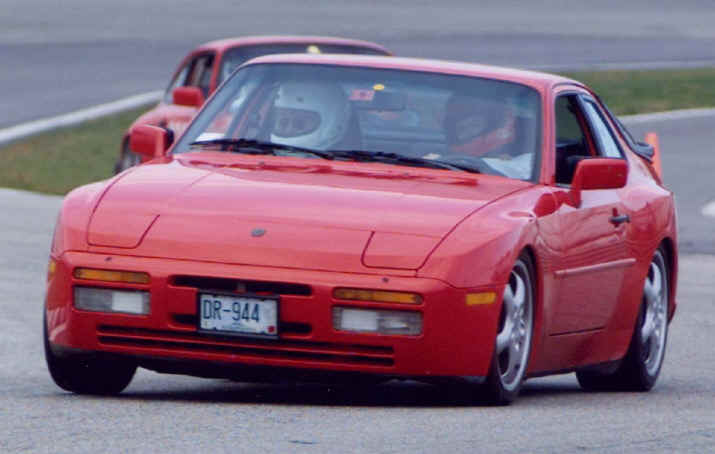 Dave Ryan
Dave's 1986 944-T 

This photo is of me at the wheel with my instructor going into turn two at NHIS during the last DE event this year. Shortly after that run, I was signed off to run solo in Yellow. 

The car is a 1986 944 turbo, 85,000 miles, I'm the 3rd owner, it has always been in New England, I've added a Stage II chip, Cup car sway bars, stiffer springs, Koni adjustable shocks and 17" wheels. Plan to keep it pretty much as is but would like to boost the power to about 325HP. 
